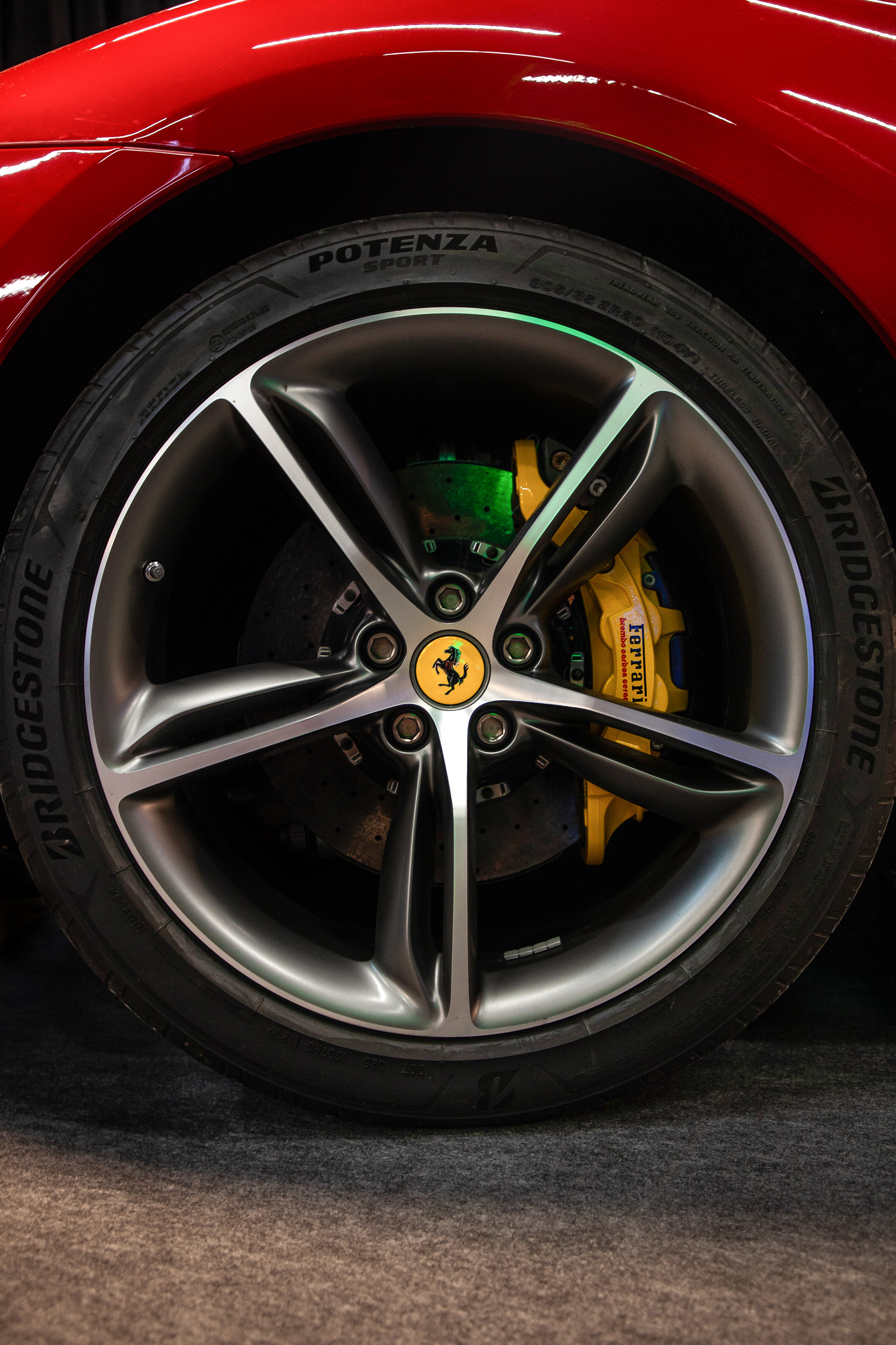 Rad- und Bremssattel-Detail eines roten Ferrari mit gelben Brembo-Bremsen