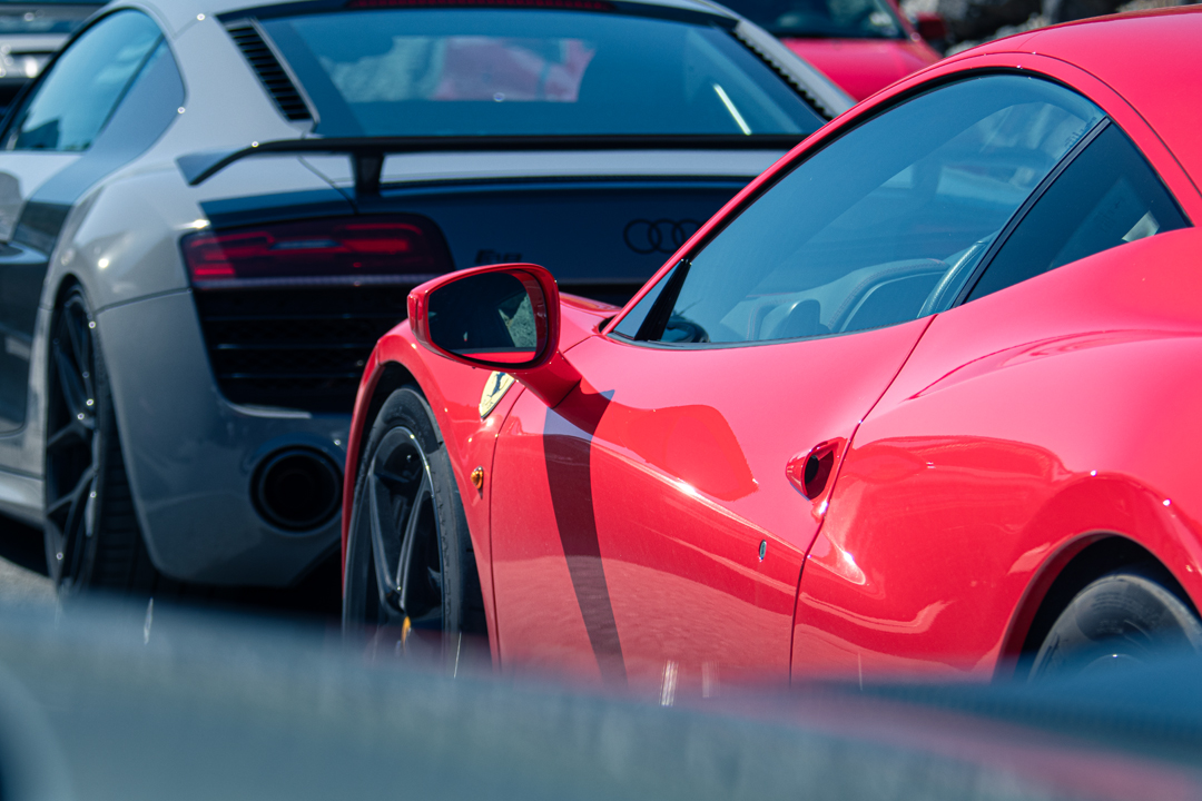 Seitenspiegel-Detail eines roten Ferrari, im Hintergrund ein Audi R8