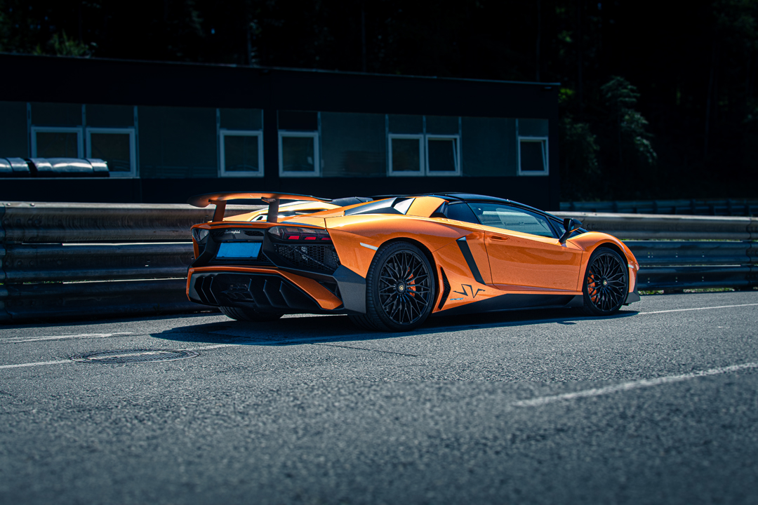 Oranger Lamborghini Aventador SV auf der Rennstrecke, Seiten-Heckansicht