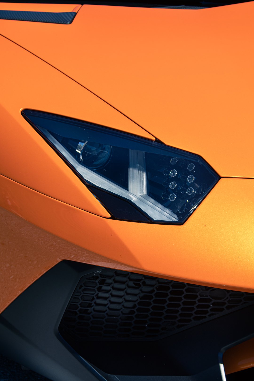 Scheinwerfer-Detail eines orangen Lamborghini Aventador SV