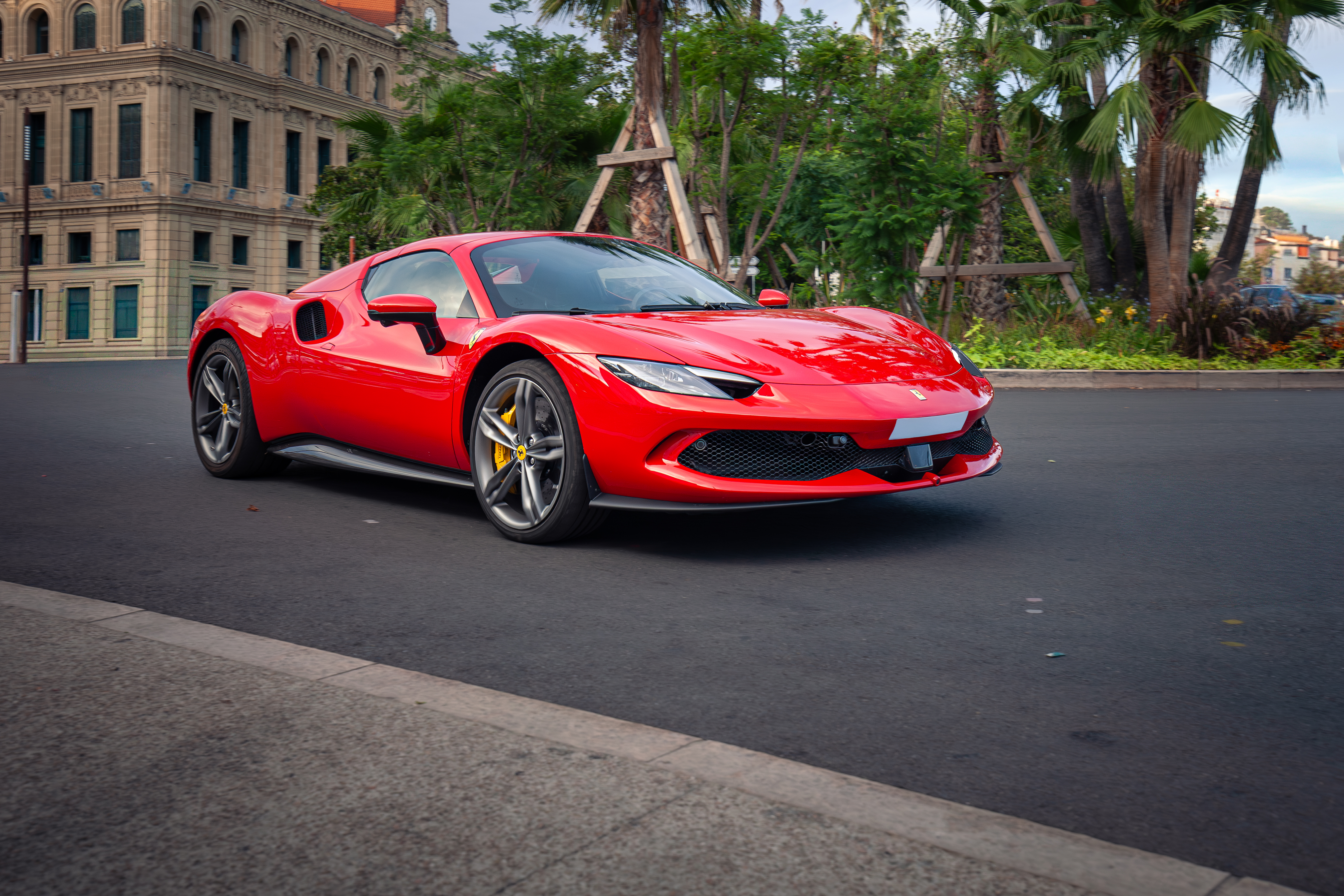 Roter Ferrari 296 GTB auf der Straße in Cannes, Palmen im Hintergrund