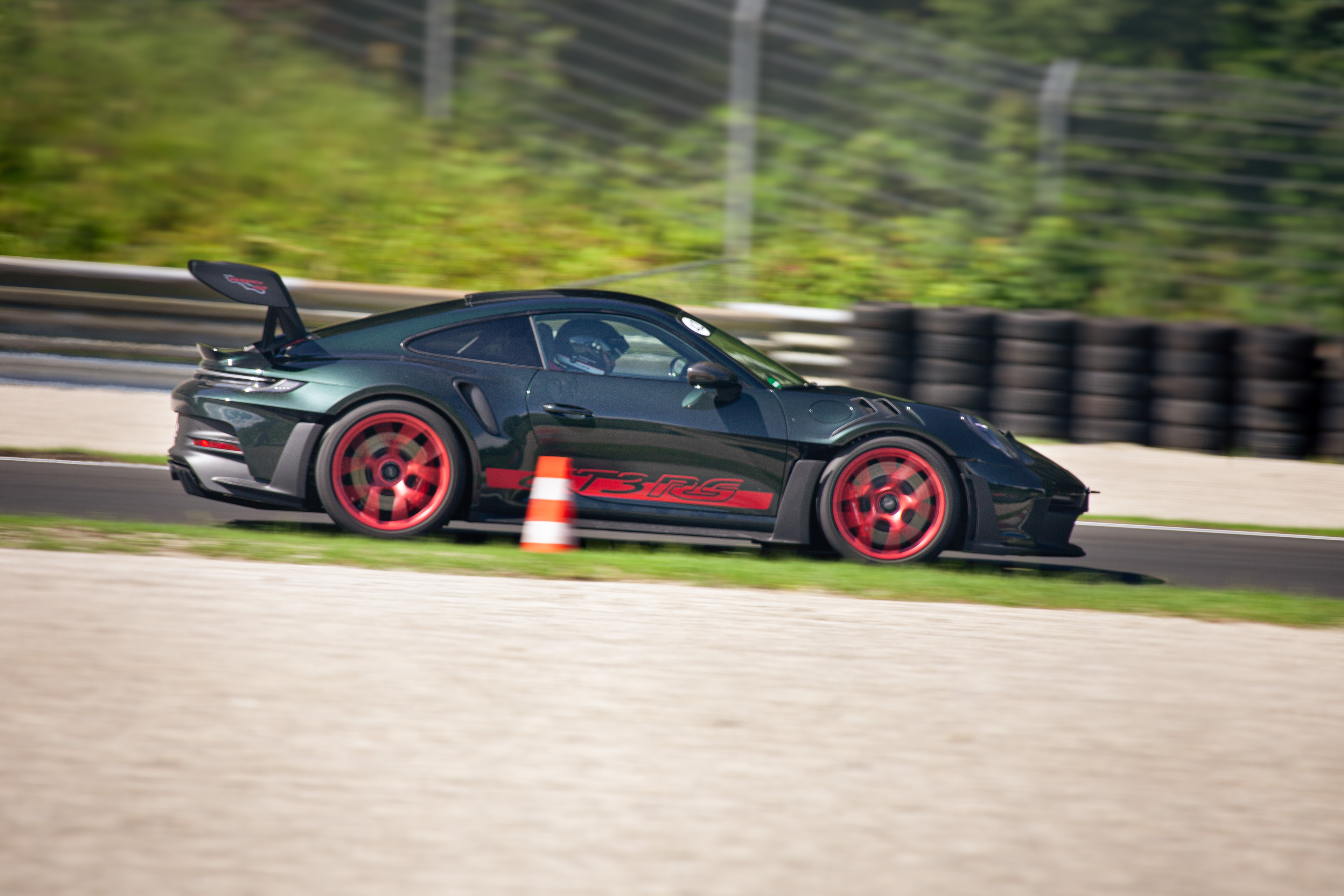 Dunkelgrüner Porsche 911 GT3 RS mit roten Felgen auf der Rennstrecke