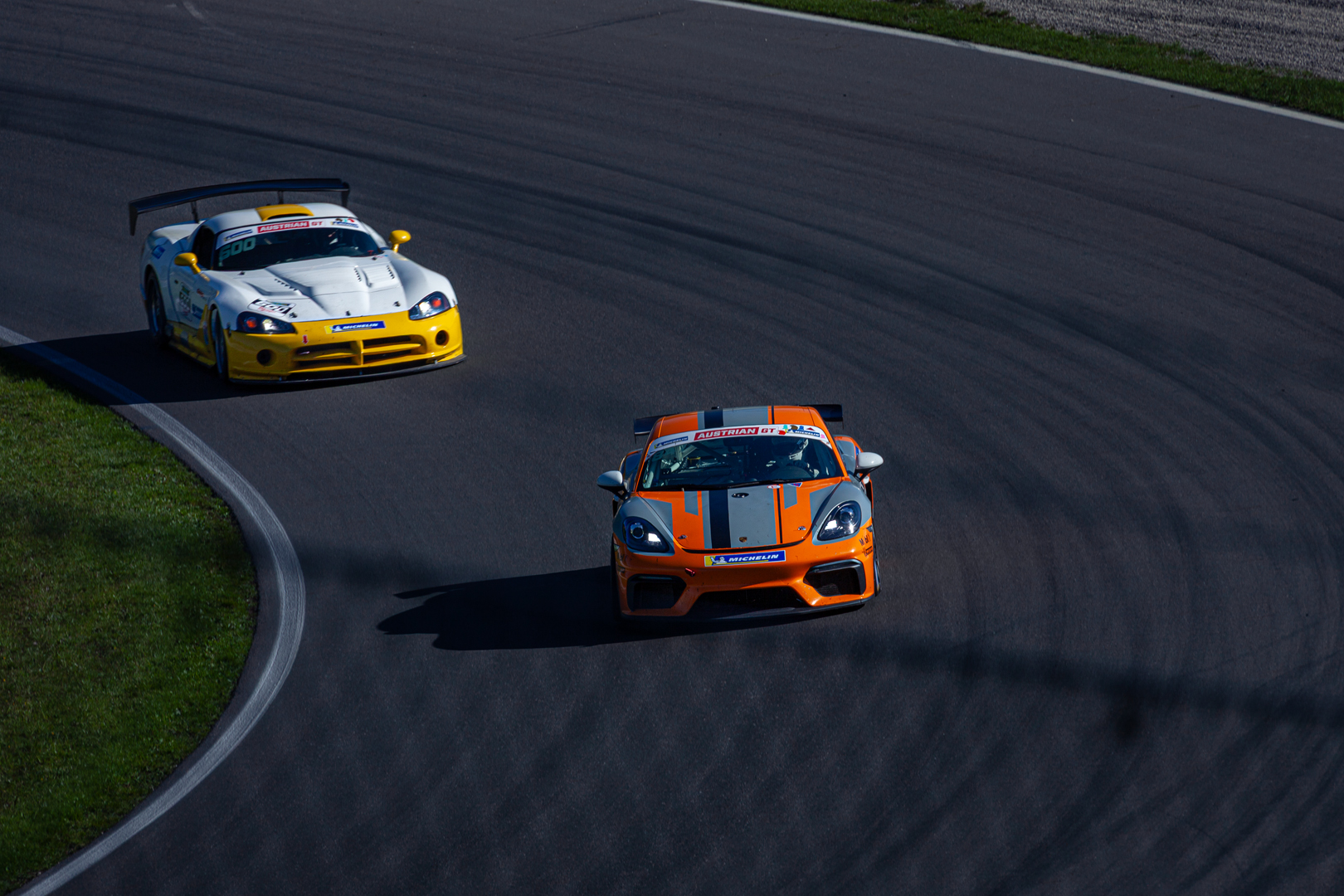 Weißer Dodge Viper GTS-R und oranger Porsche Cayman GT4 in der Kurve