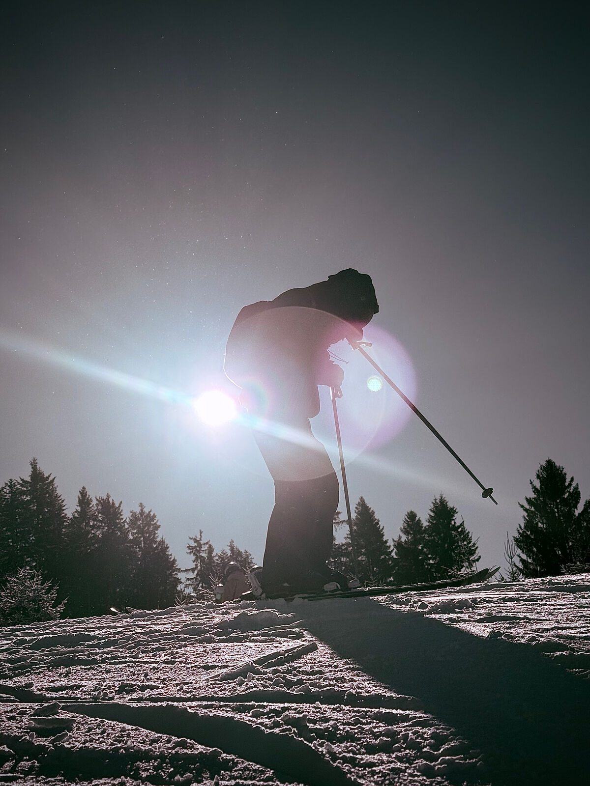 Skifahrer im Gegenlicht mit Schneestaub