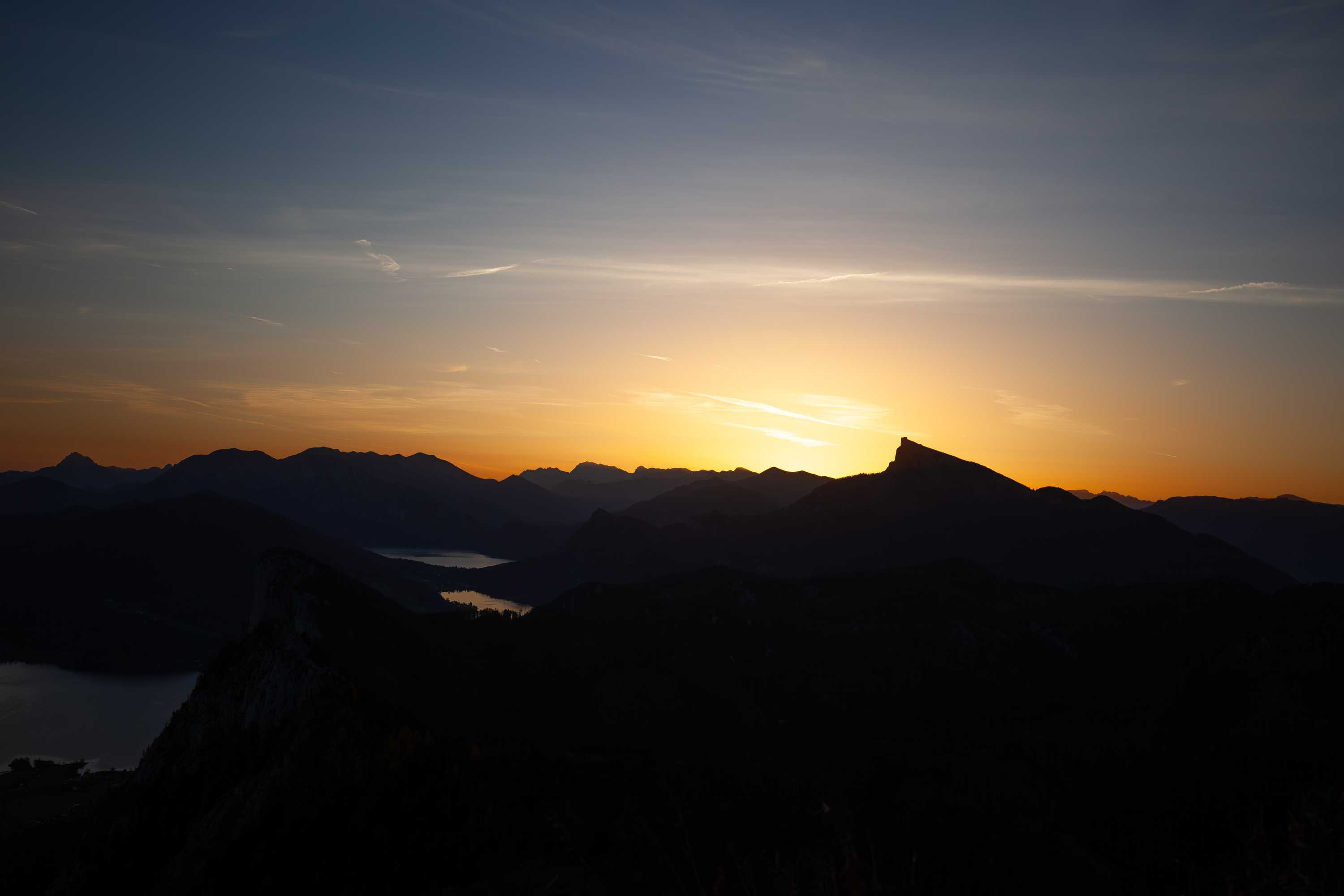 Alpen-Silhouette bei Sonnenuntergang mit Bergsee im Tal
