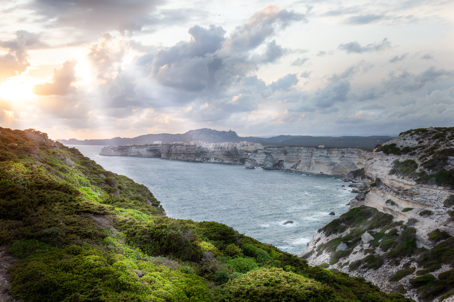 Weiße Kalksteinklippen von Bonifacio, Korsika, mit Bucht und Wolkenhimmel