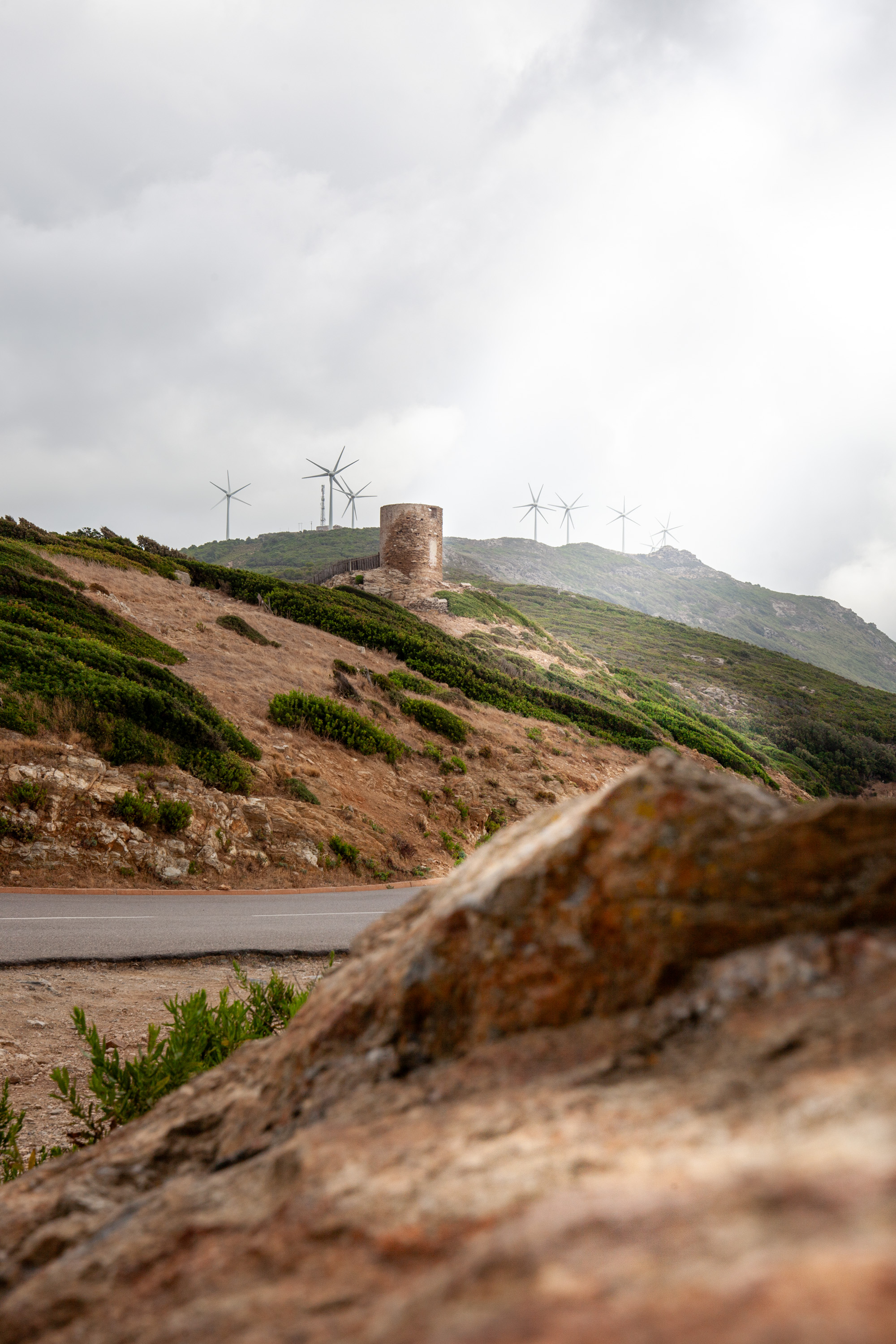 Genueser Turm auf einem Hügel in Korsika, im Hintergrund Windräder